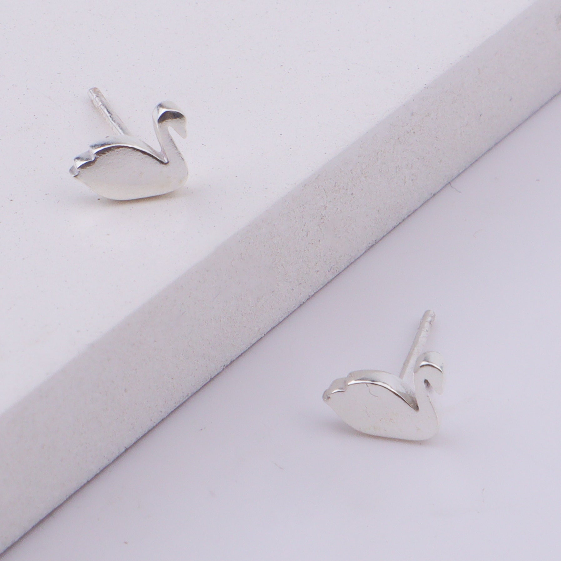 Close-up of silver swan stud earrings on display