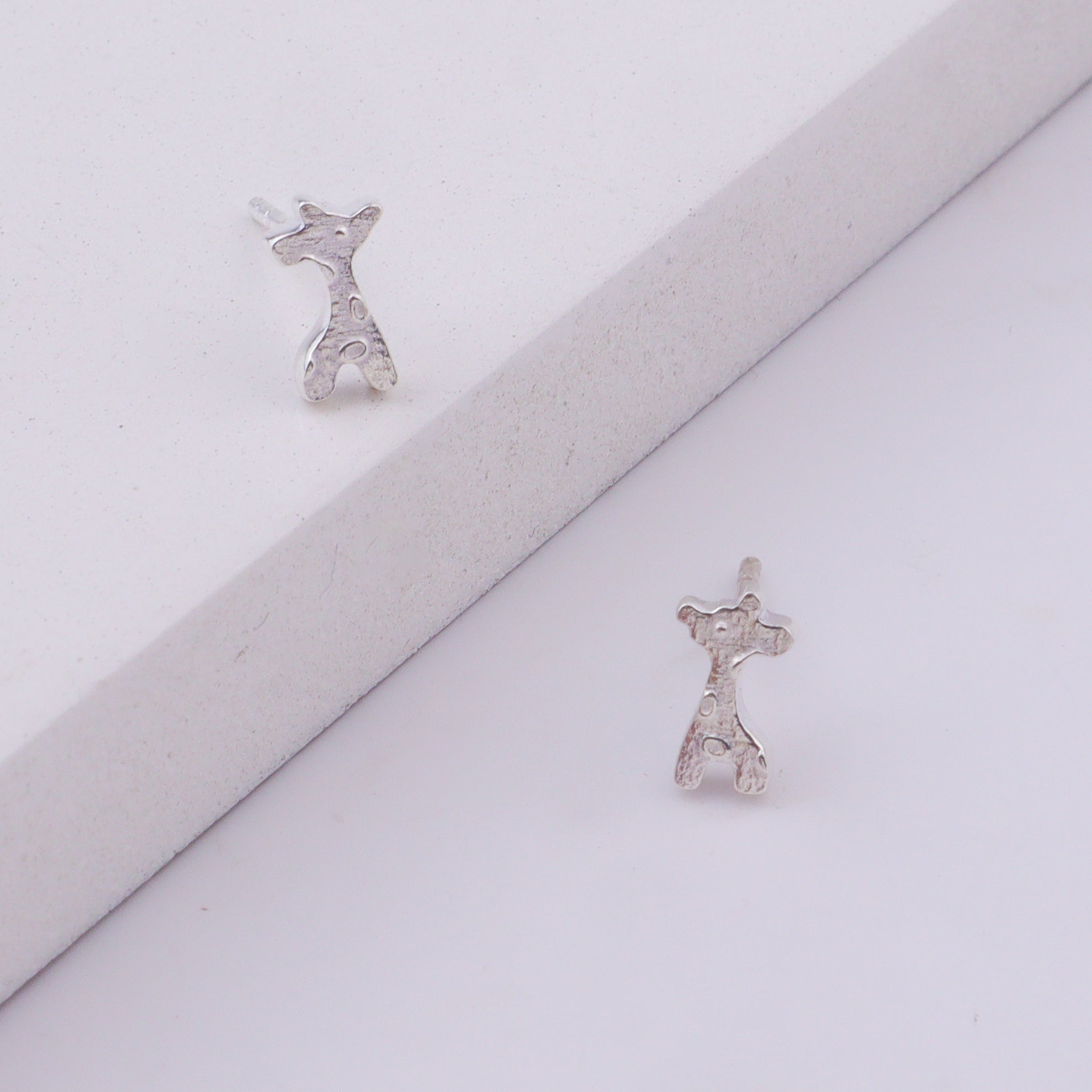 Close-up of silver giraffe stud earrings on ear
