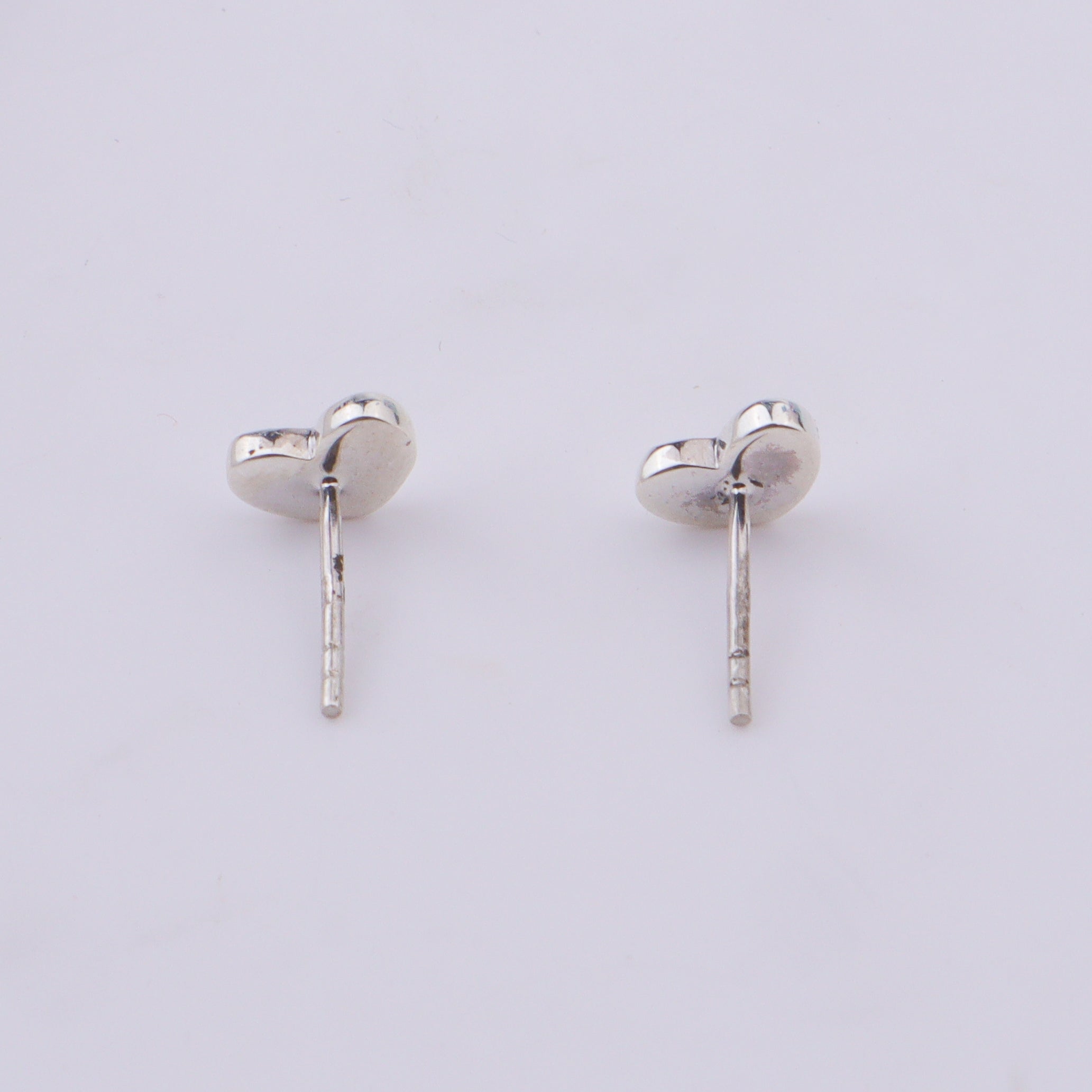 Silver heart stud earrings on white background
