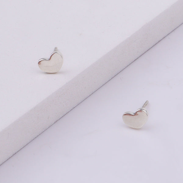 Close-up of silver heart stud earrings on display