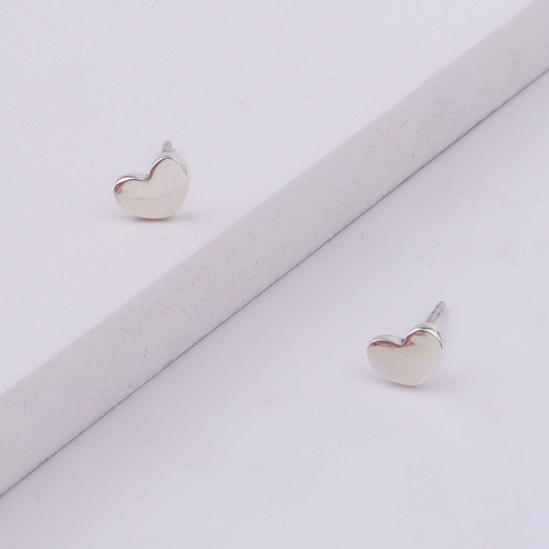 Close-up of silver heart stud earrings on display