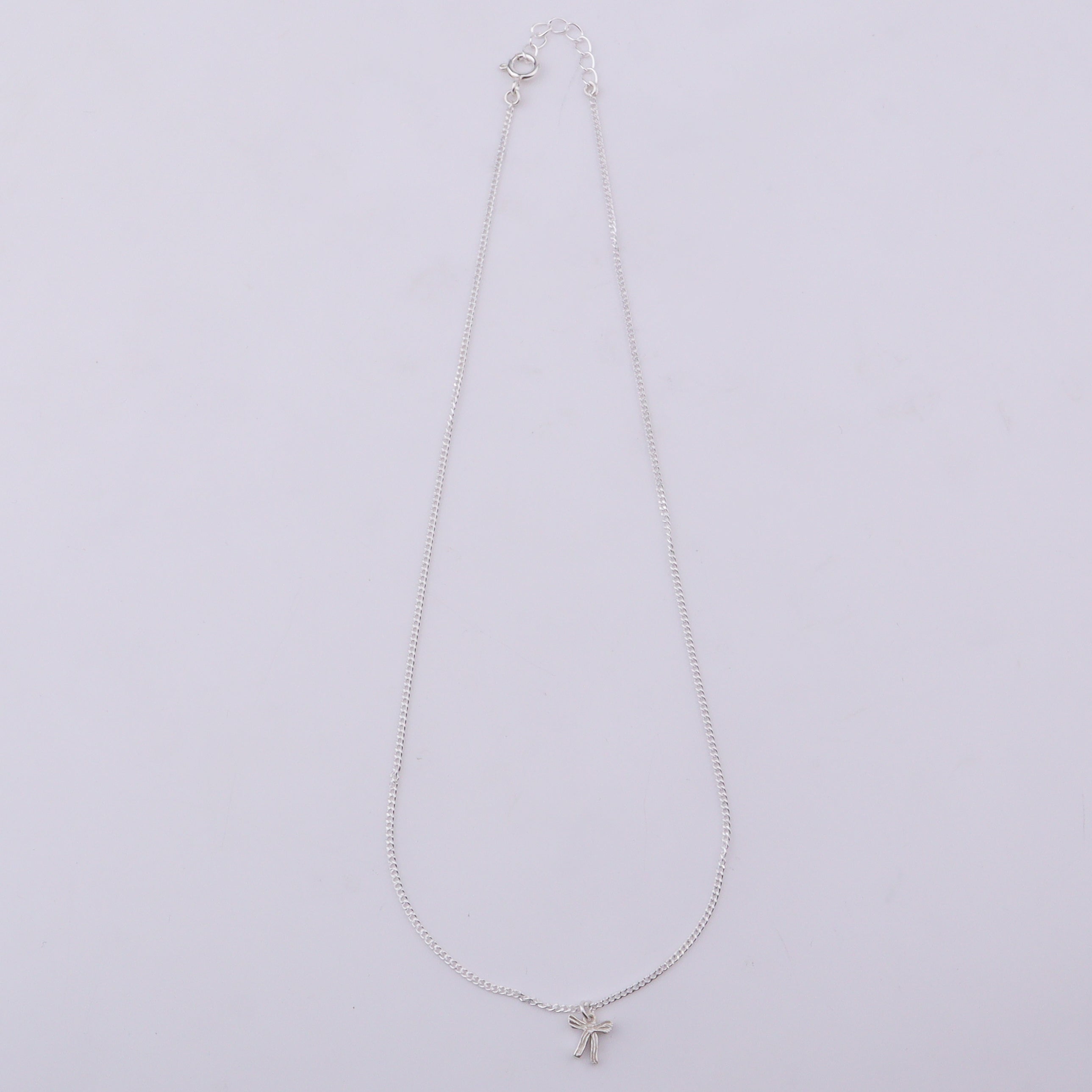 Silver necklace with bow pendant on white background