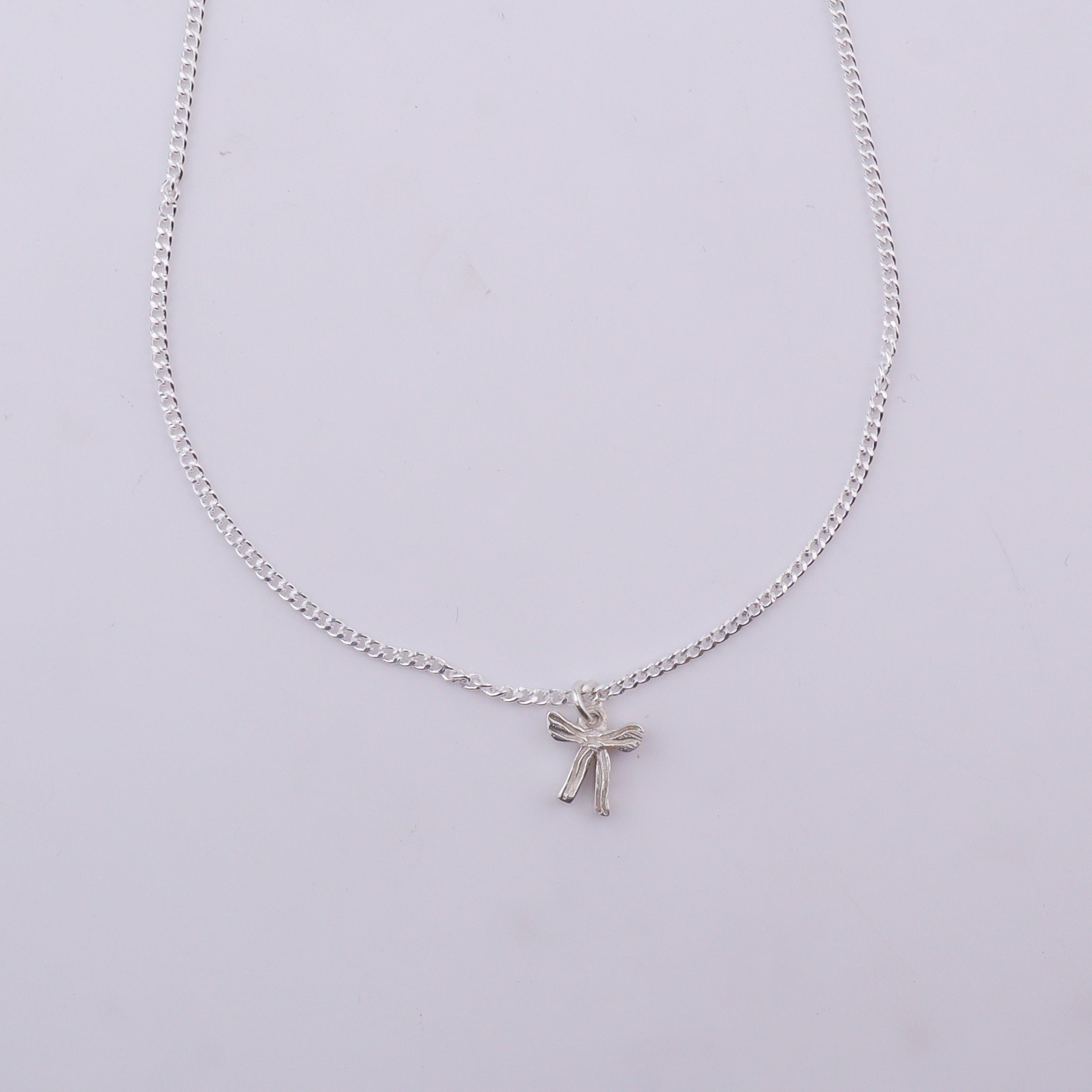 Close-up of silver chain with bow pendant