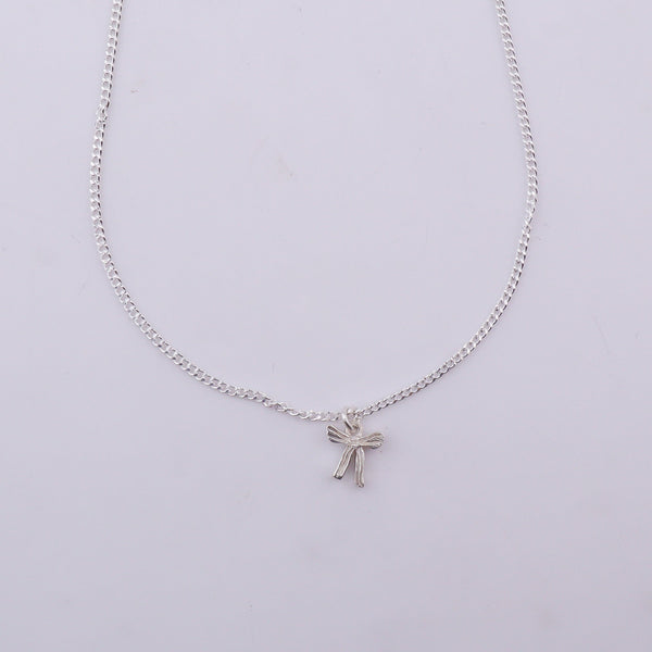 Close-up of silver chain with bow pendant