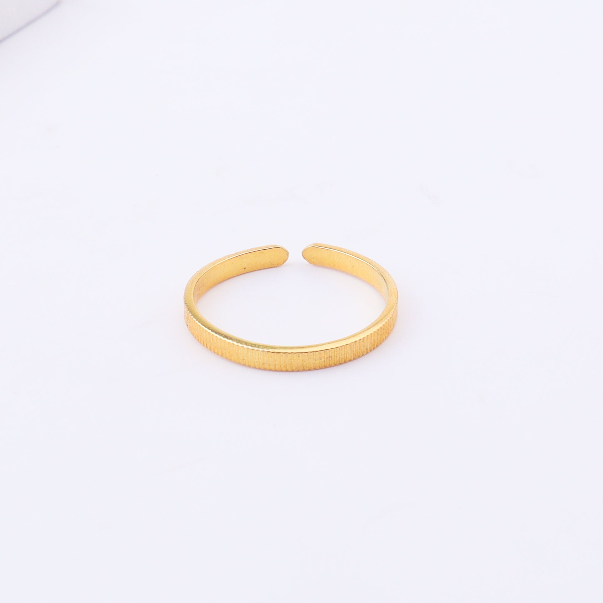 Gold textured open cuff bracelet on white surface