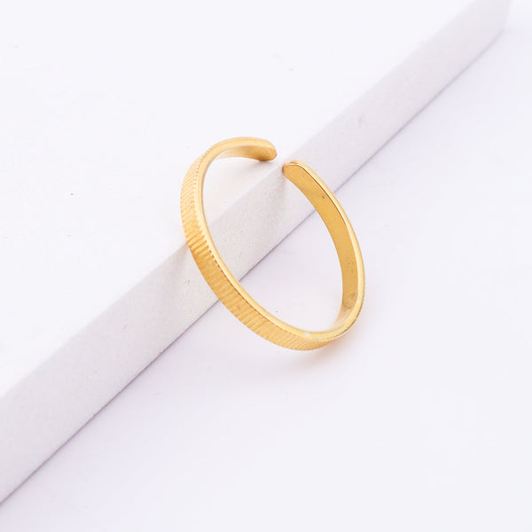 Gold textured open cuff bracelet on white surface
