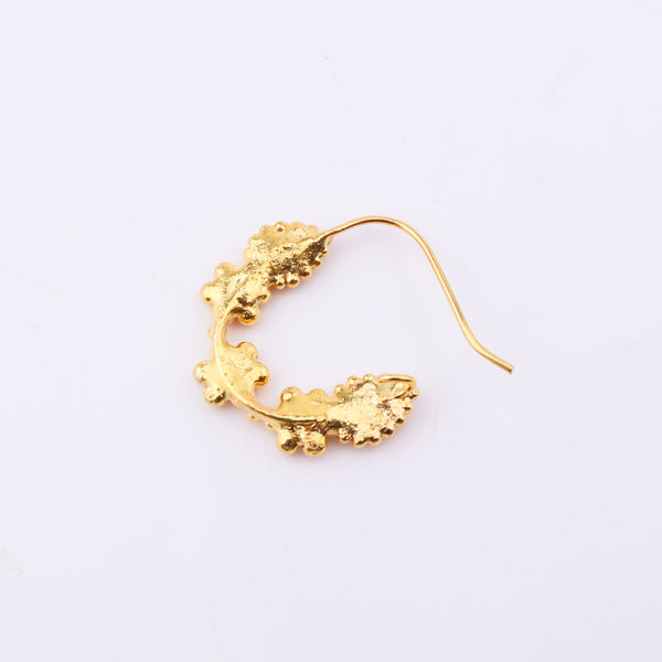 Gold nose ring on white surface highlighting fine jewelry details