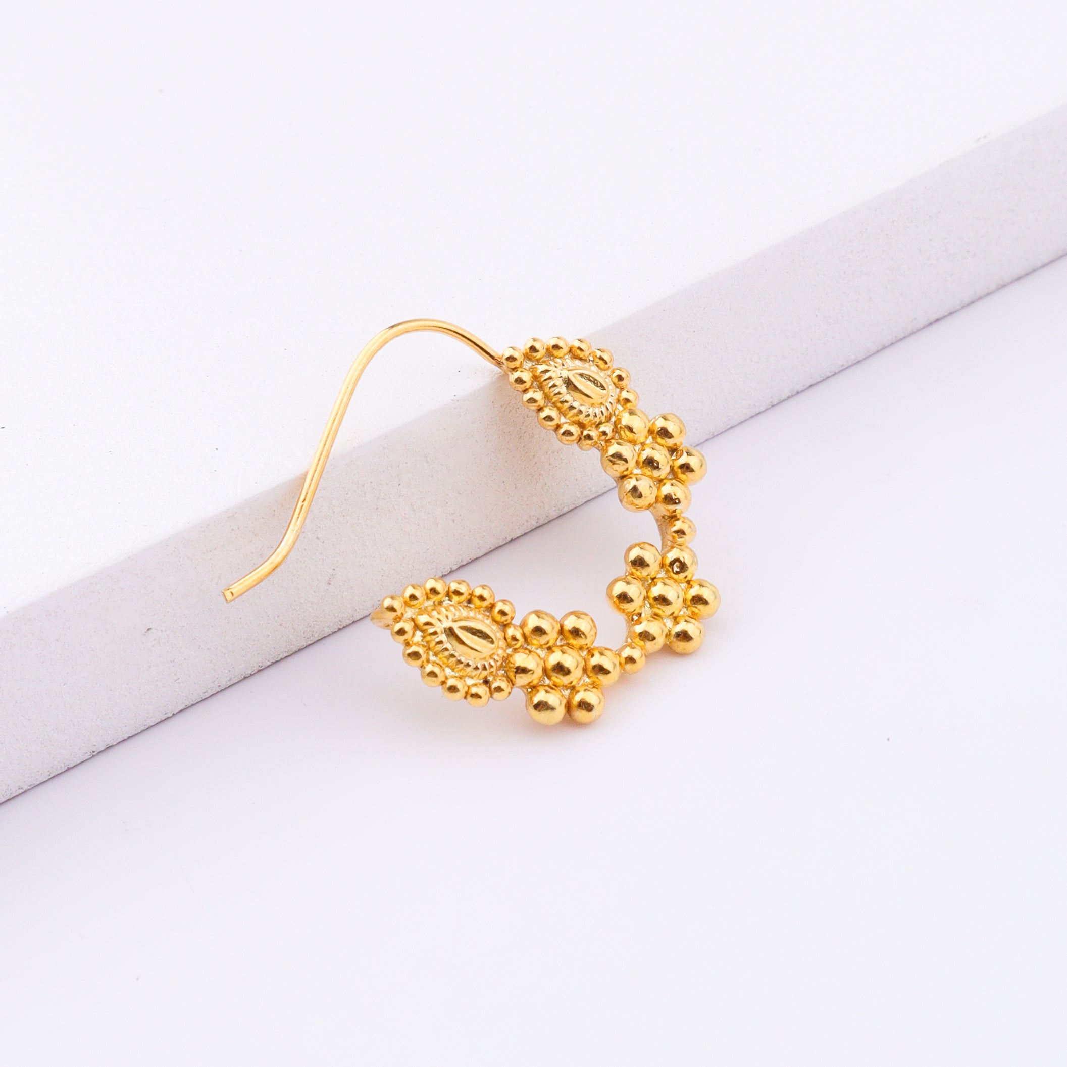 Gold nose ring displayed on white background for jewelry showcase