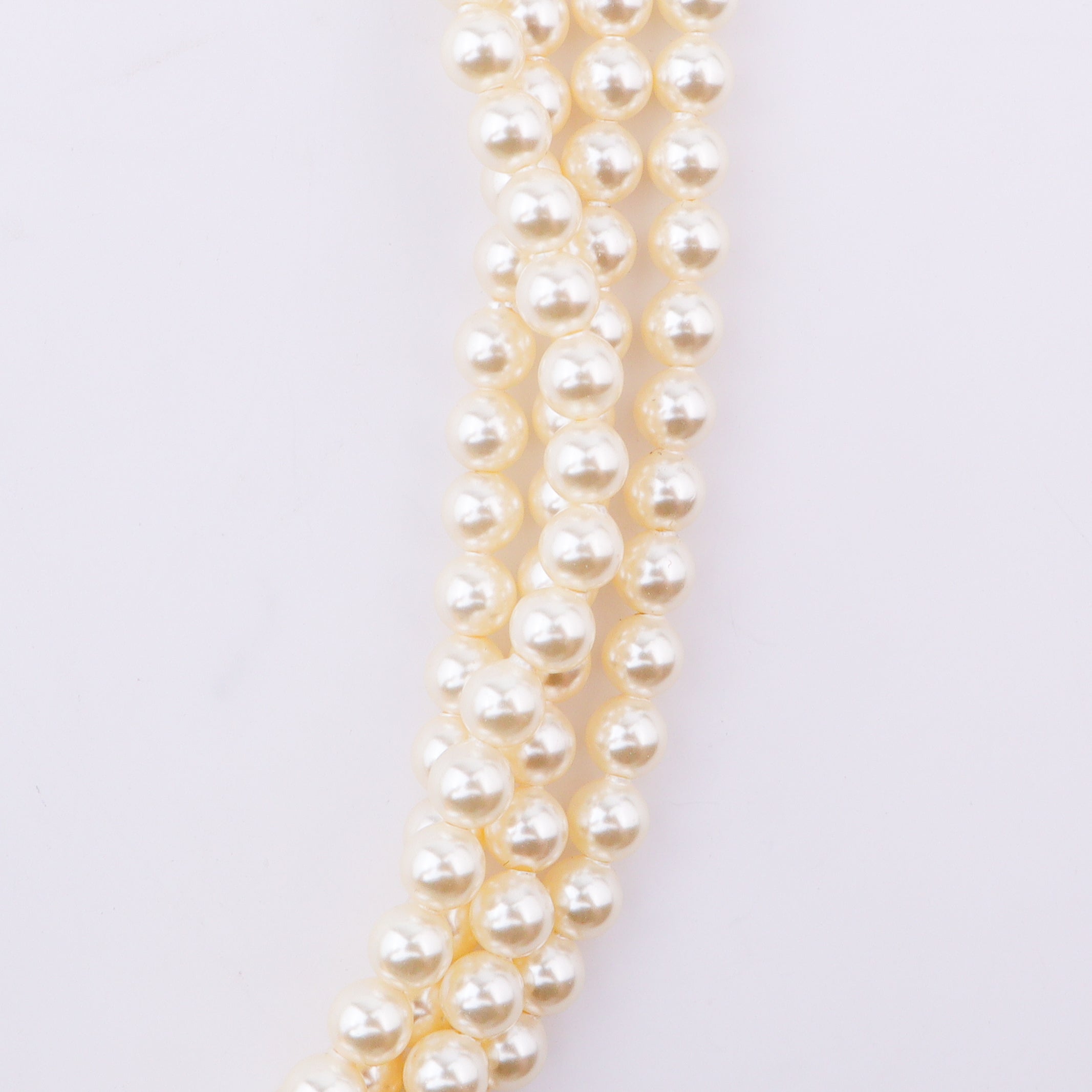 Pearl necklace with gold clasp on white surface