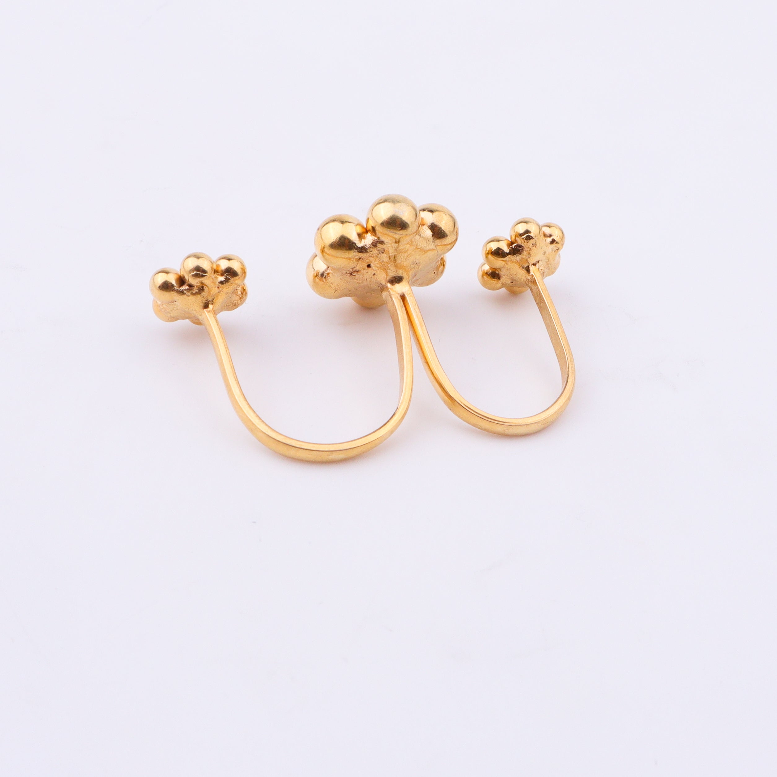 Gold plated floral cluster ring on white surface