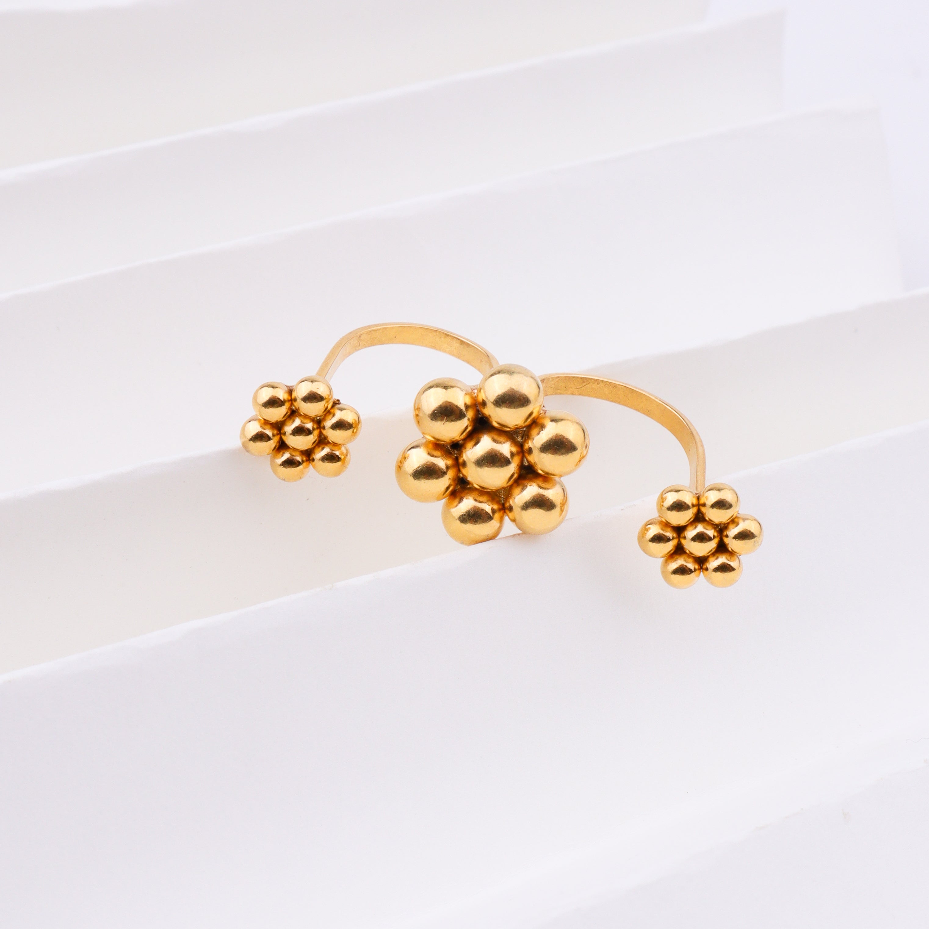 Gold plated floral cluster ring on white background