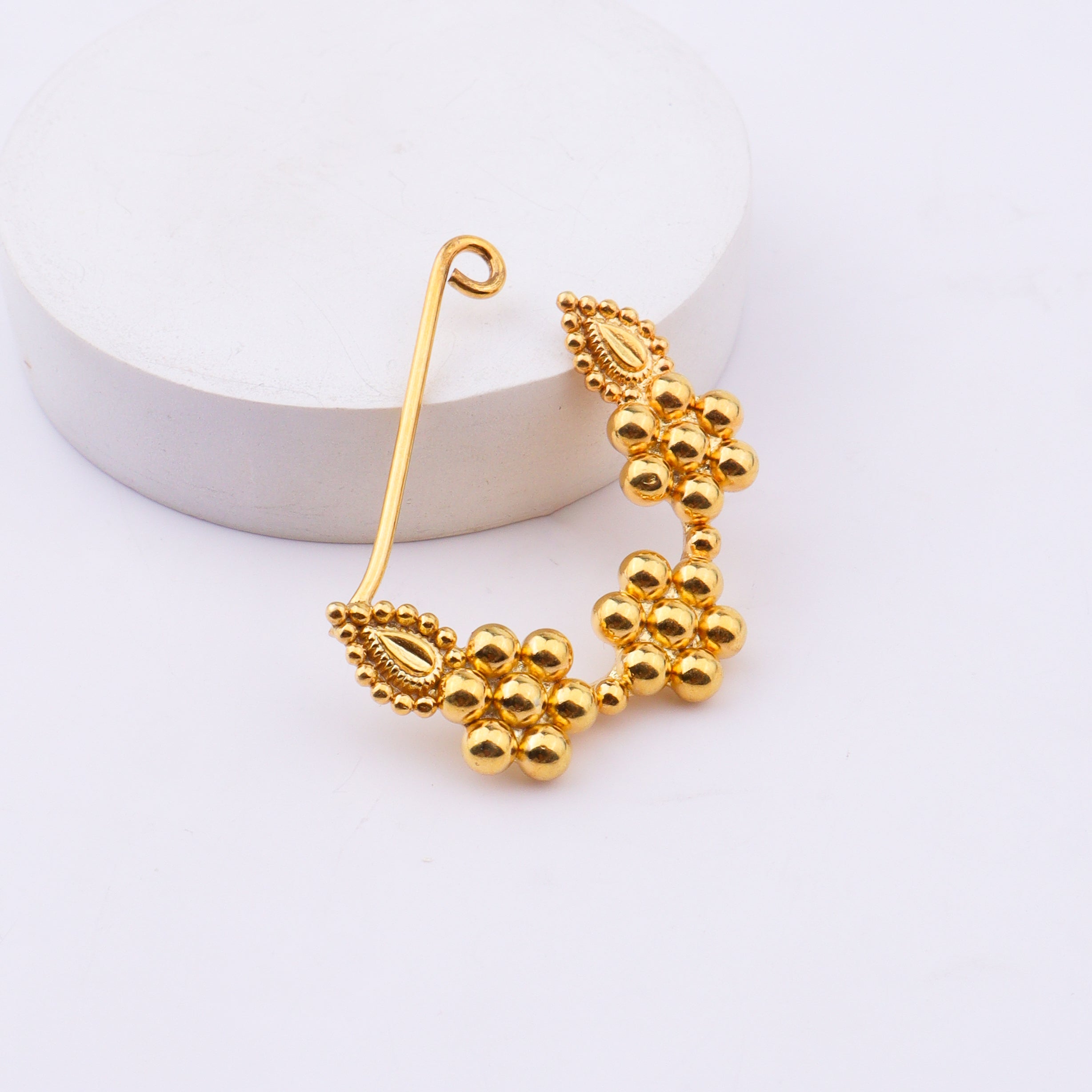 Gold nose ring on white background with certification label