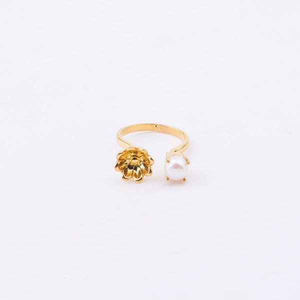 Gold flower ring with pearl on white surface