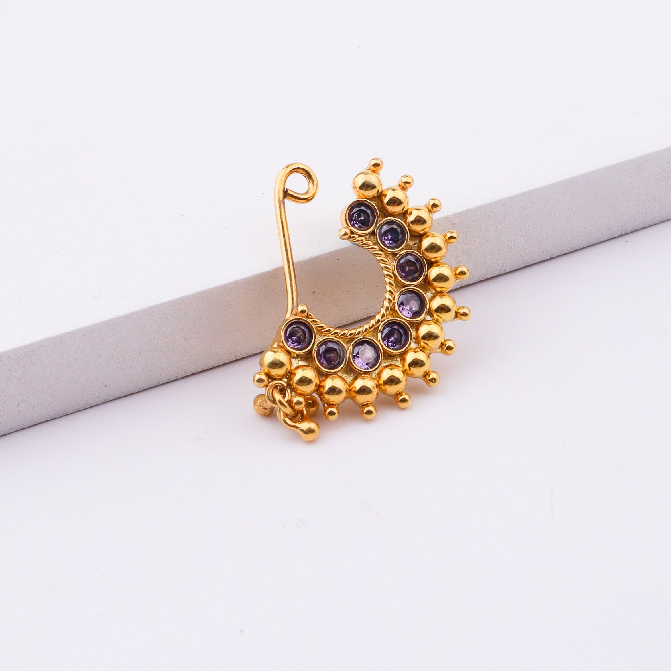 Woman wearing gold nose pin with purple stones