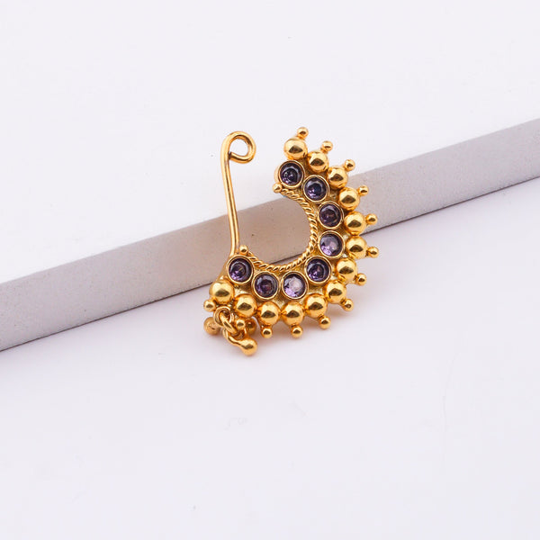Woman wearing gold nose pin with purple stones