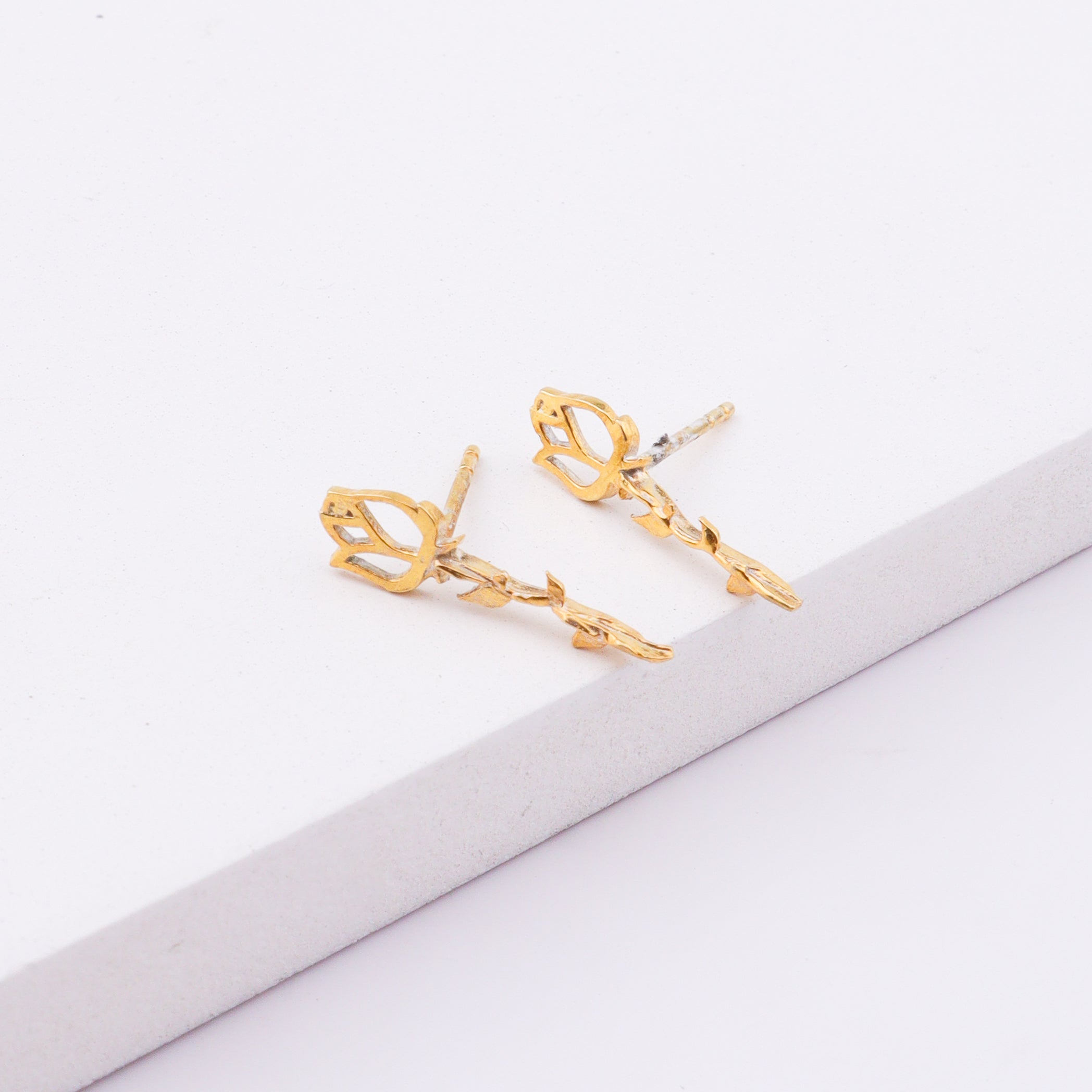 Gold floral stud earrings on white surface