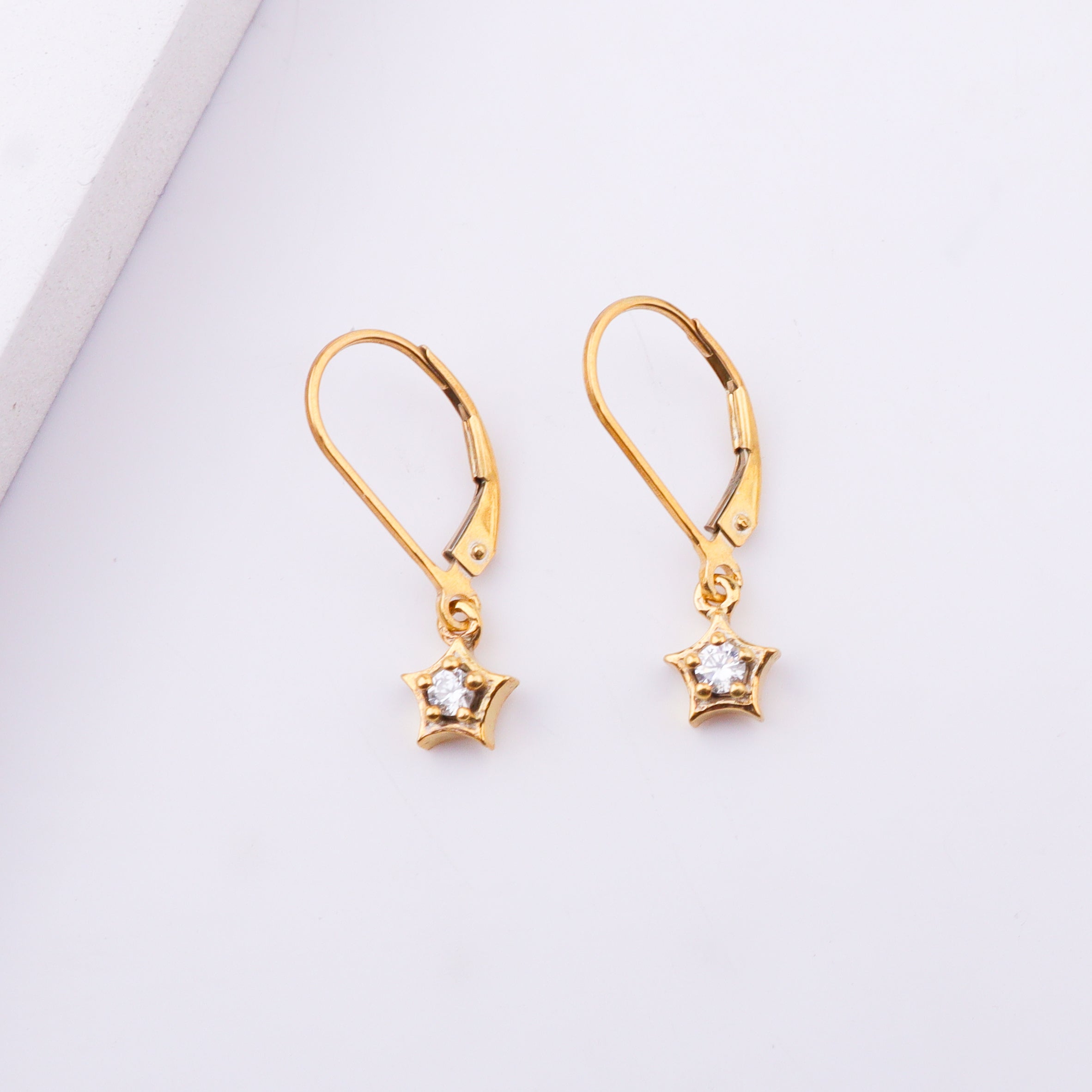 Gold star earrings with cubic zirconia stones on white background