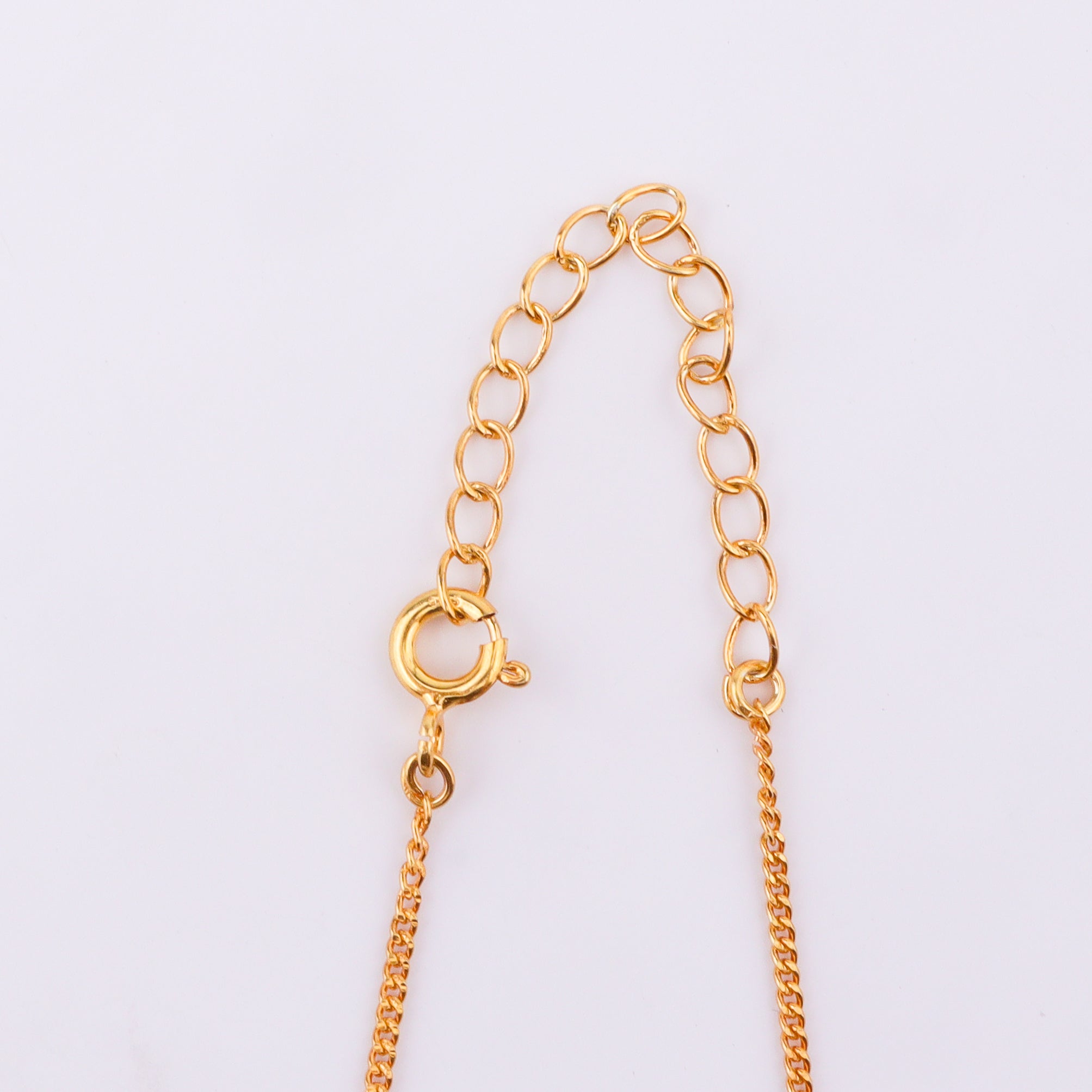 Gold chain with black beads and sun pendant on white background