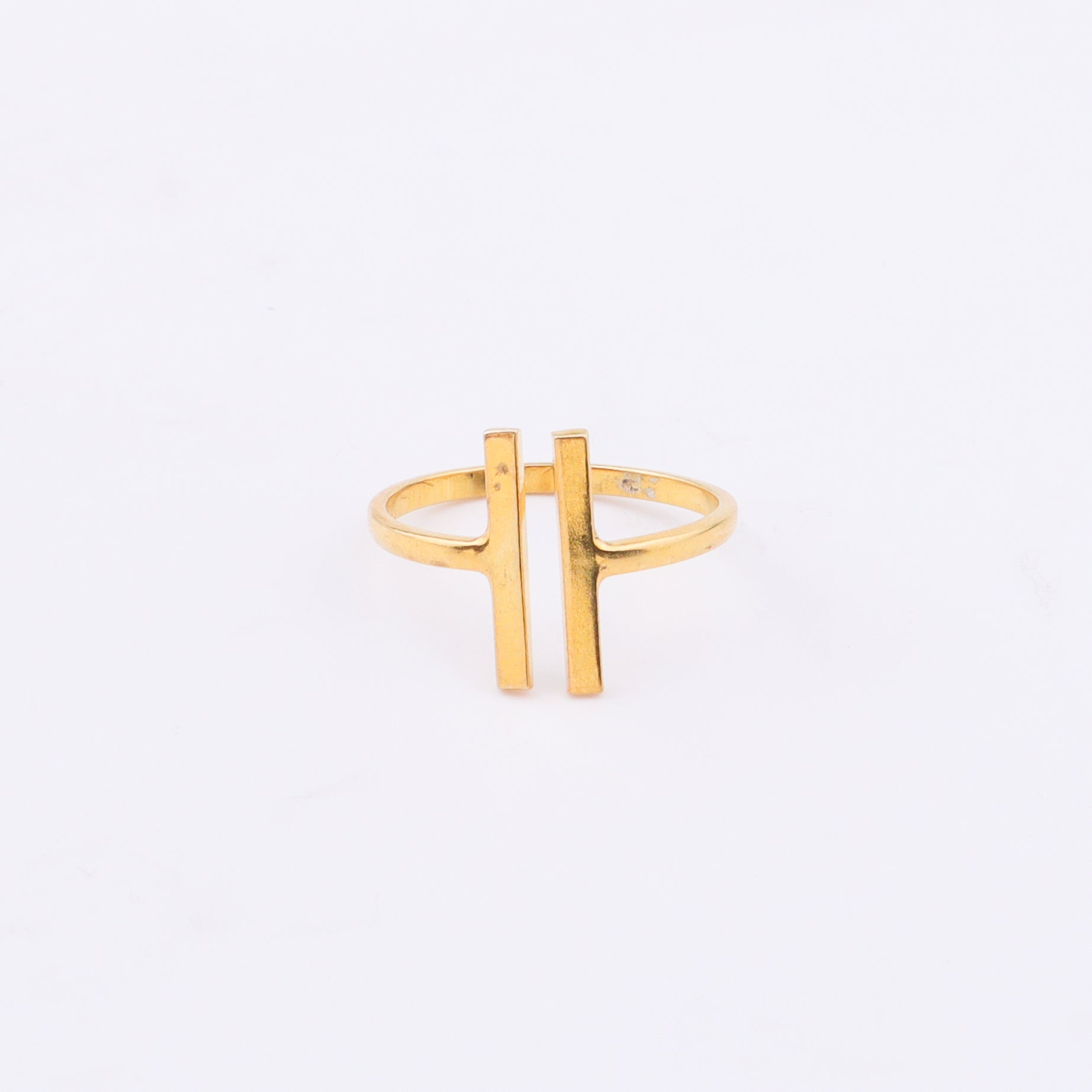 Gold ring with H-shaped design on white background