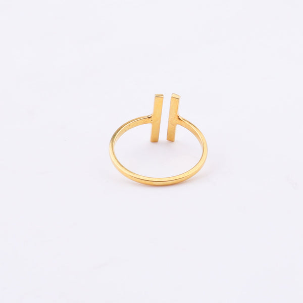 Gold ring with H-shaped design on white surface