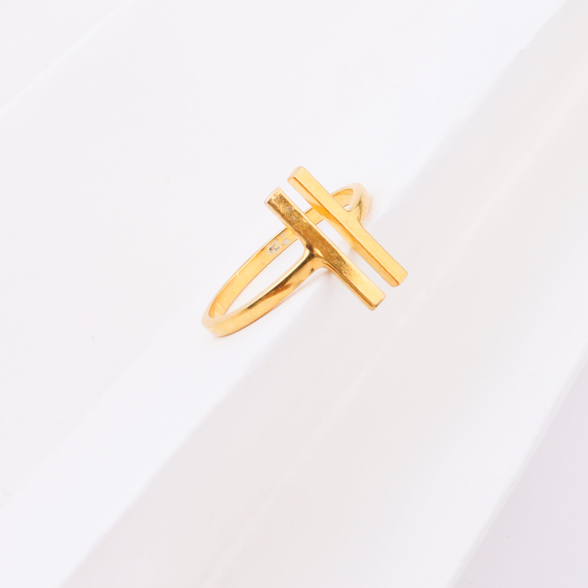 Gold ring with H-shaped design on white background