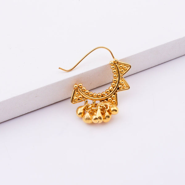 Gold star-shaped nose ring with beaded design on white surface