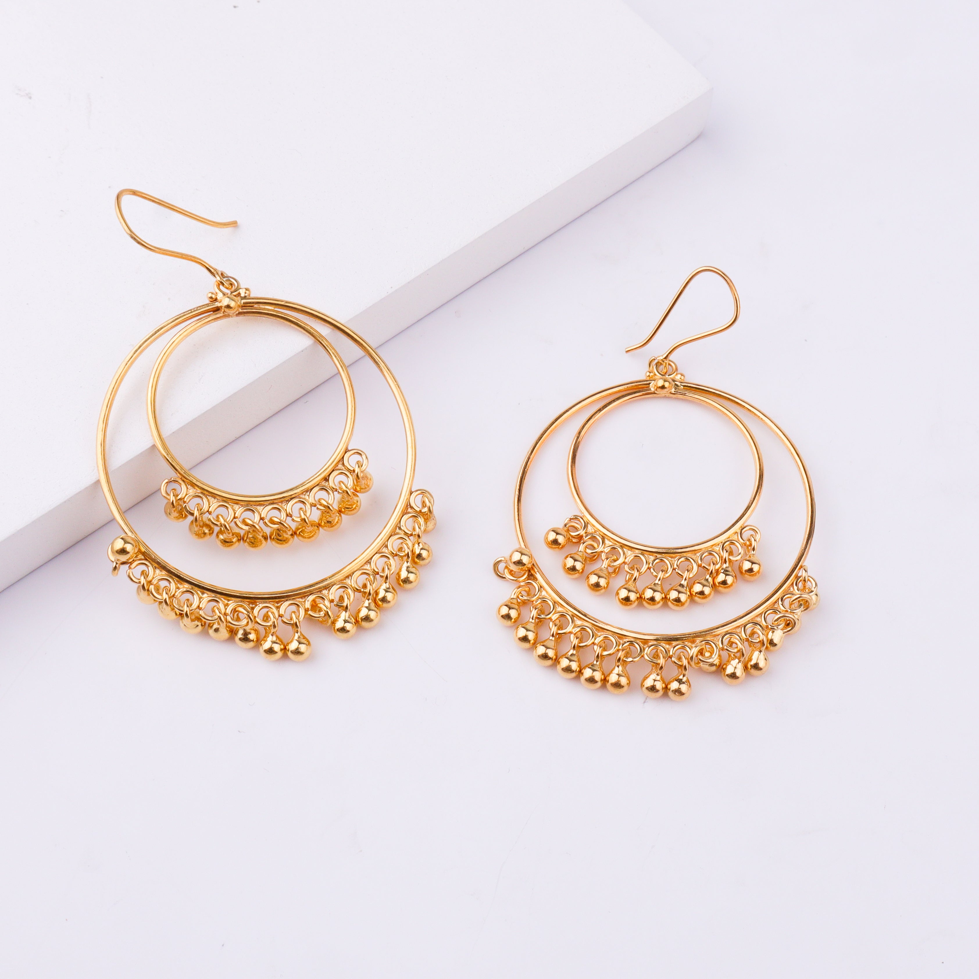 Gold earrings with hooks on white background