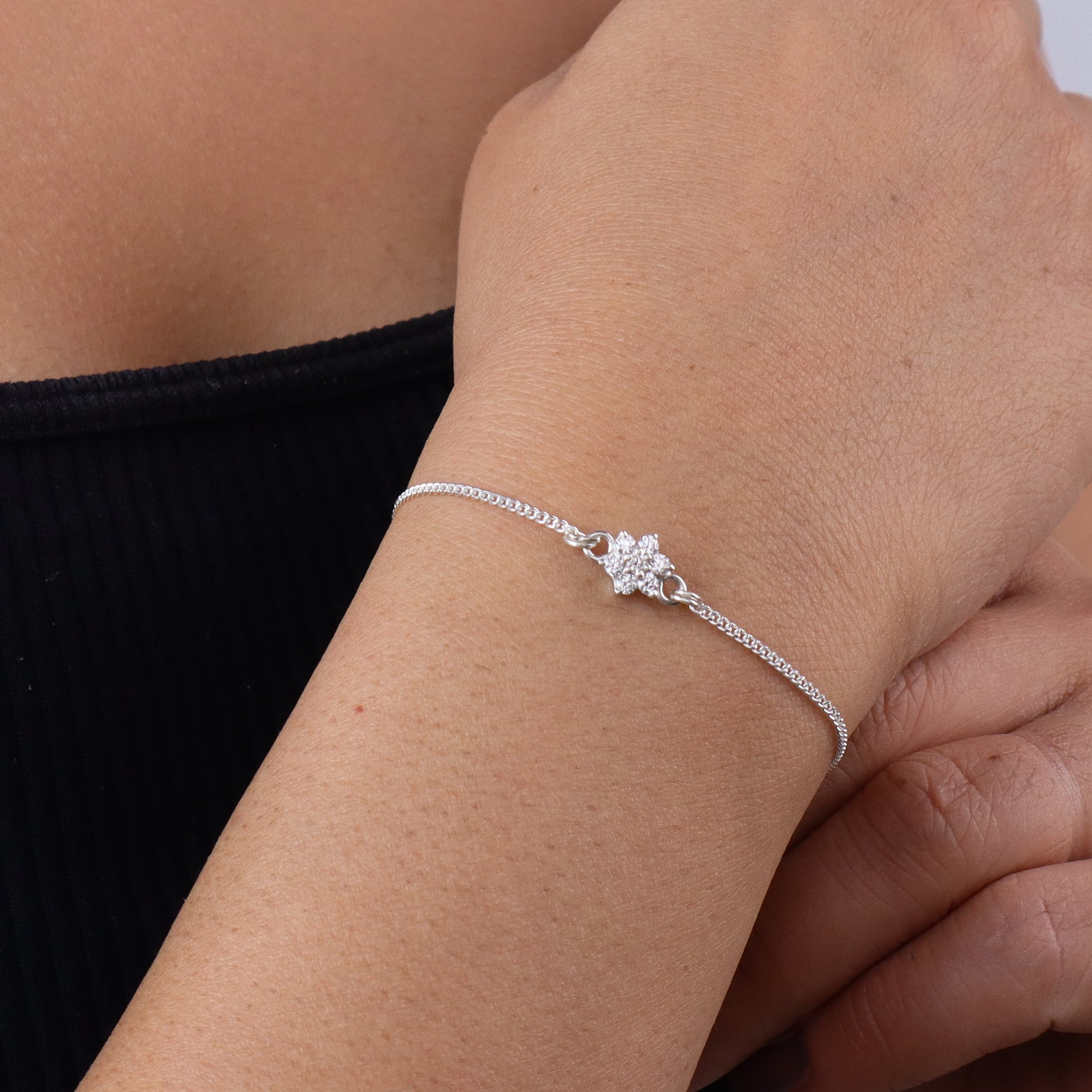 Silver bracelet with floral charm on wrist