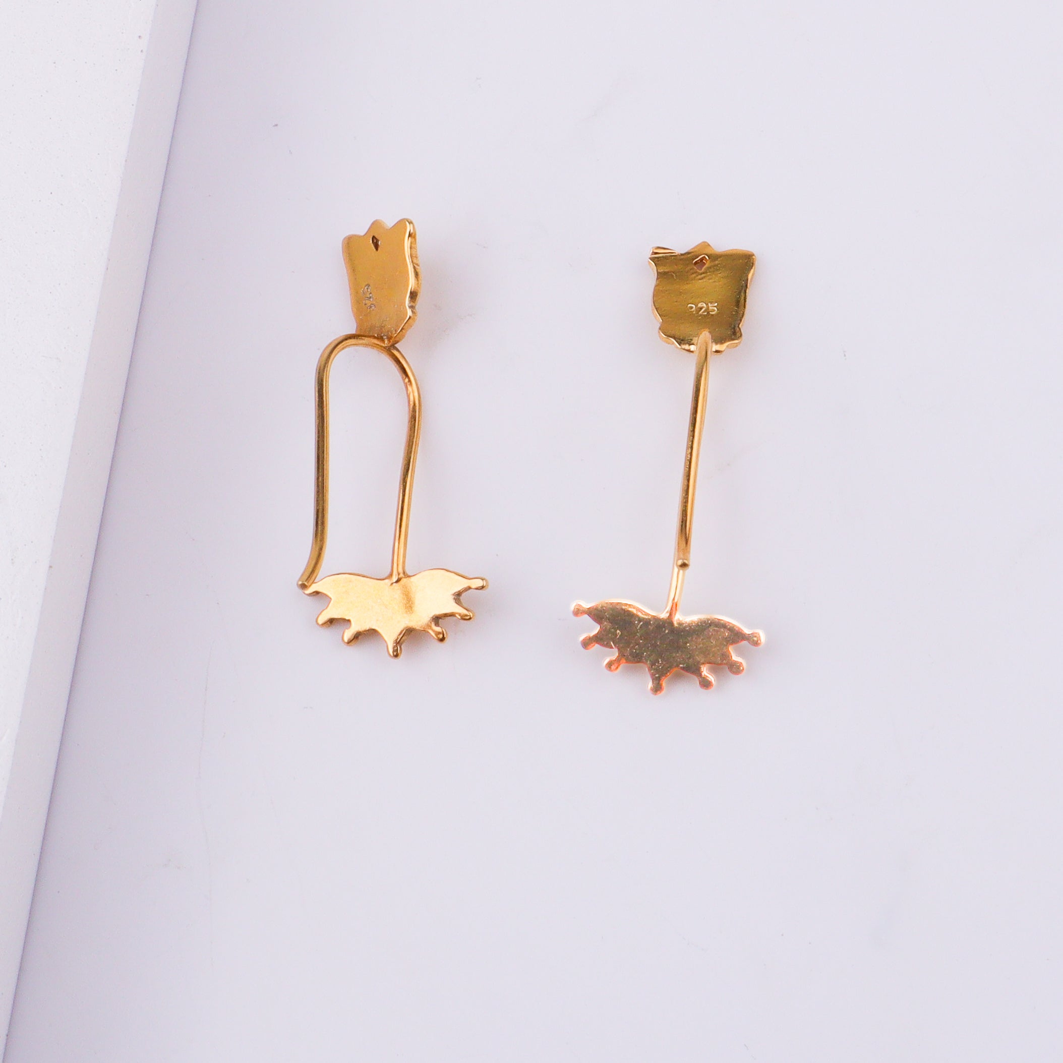 Back view of gold lotus flower clip-on earring showing hallmark