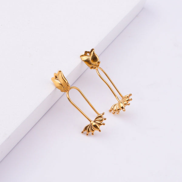 Gold lotus flower earrings displayed on white surface