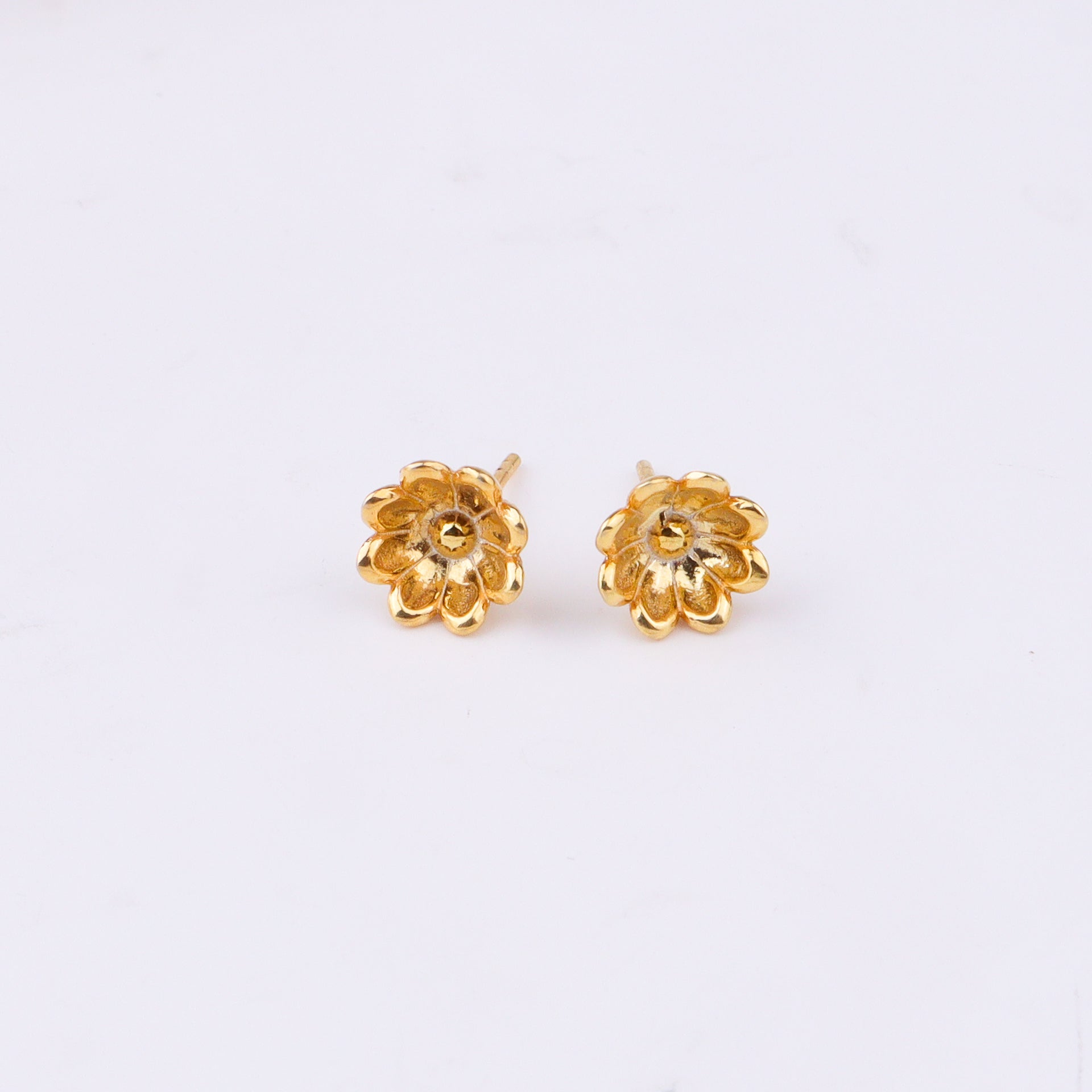 Gold flower stud earrings on white paper