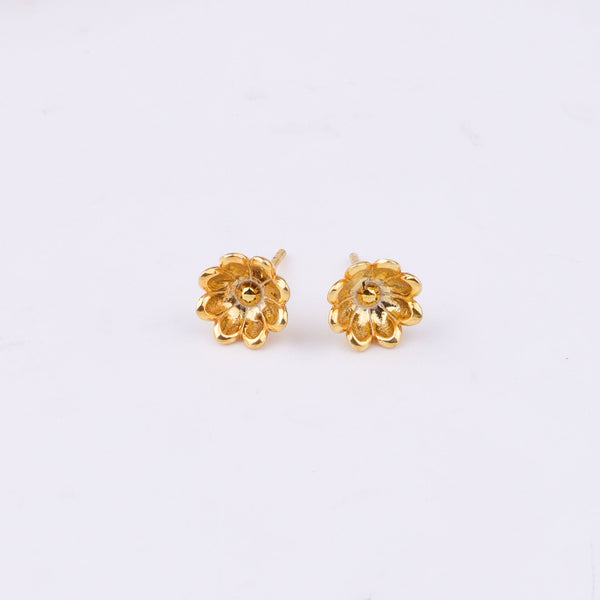 Gold flower stud earrings on white paper