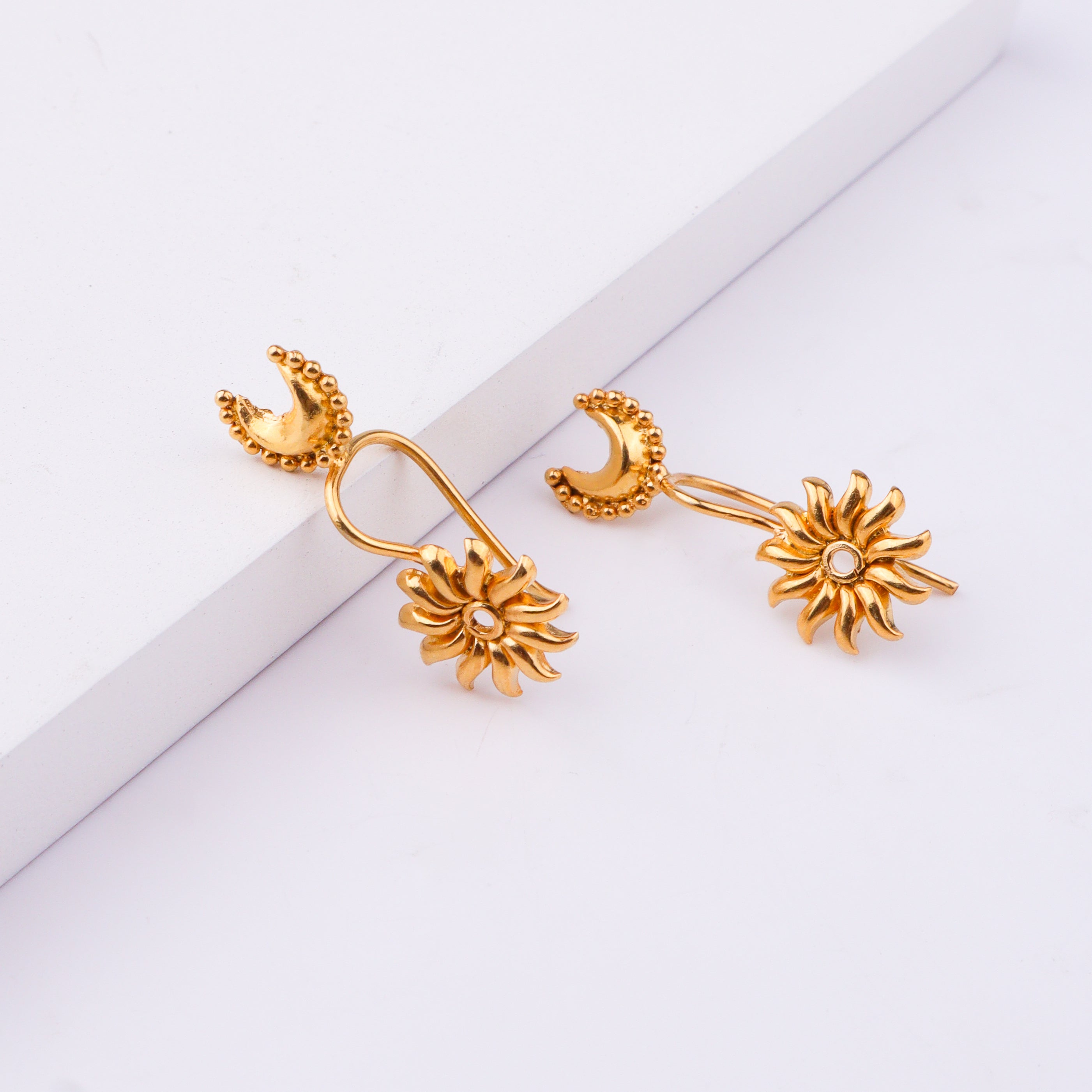 Gold moon earrings with floral motif on white background