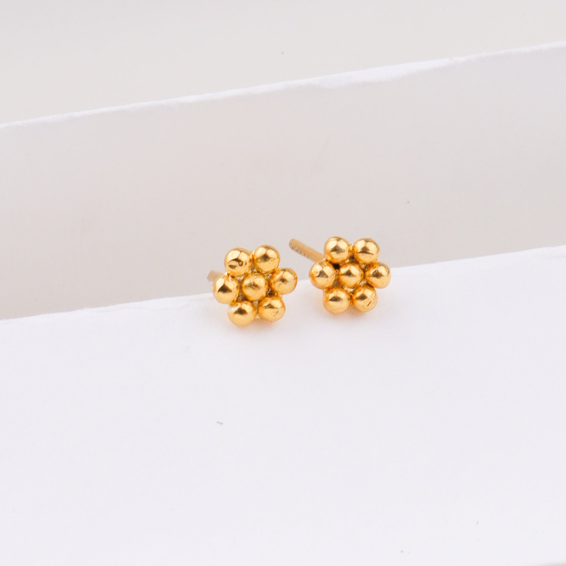 Gold earrings on white surface