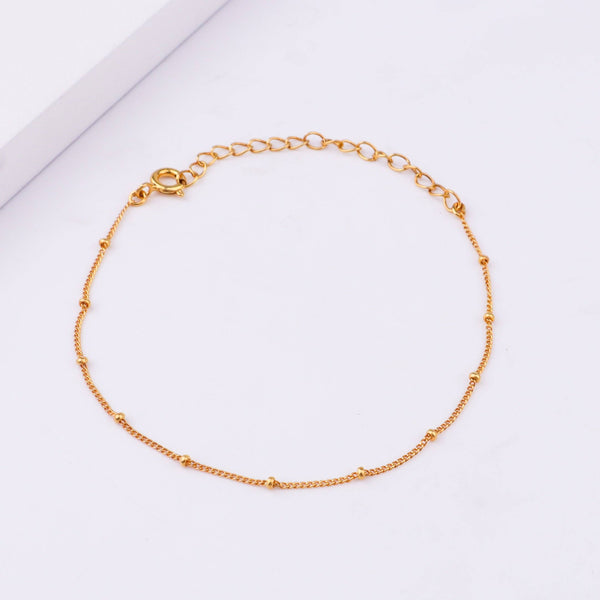 Gold chain bracelet on white background