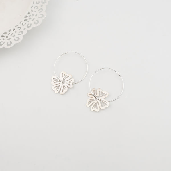 Silver flower earrings with hoop design, worn on ear, jewelry accessory