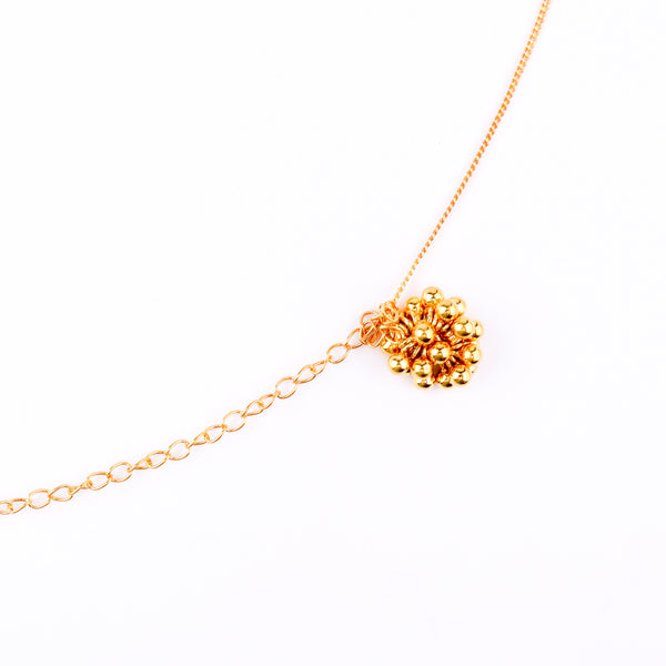 Gold chain with floral pendant on white background