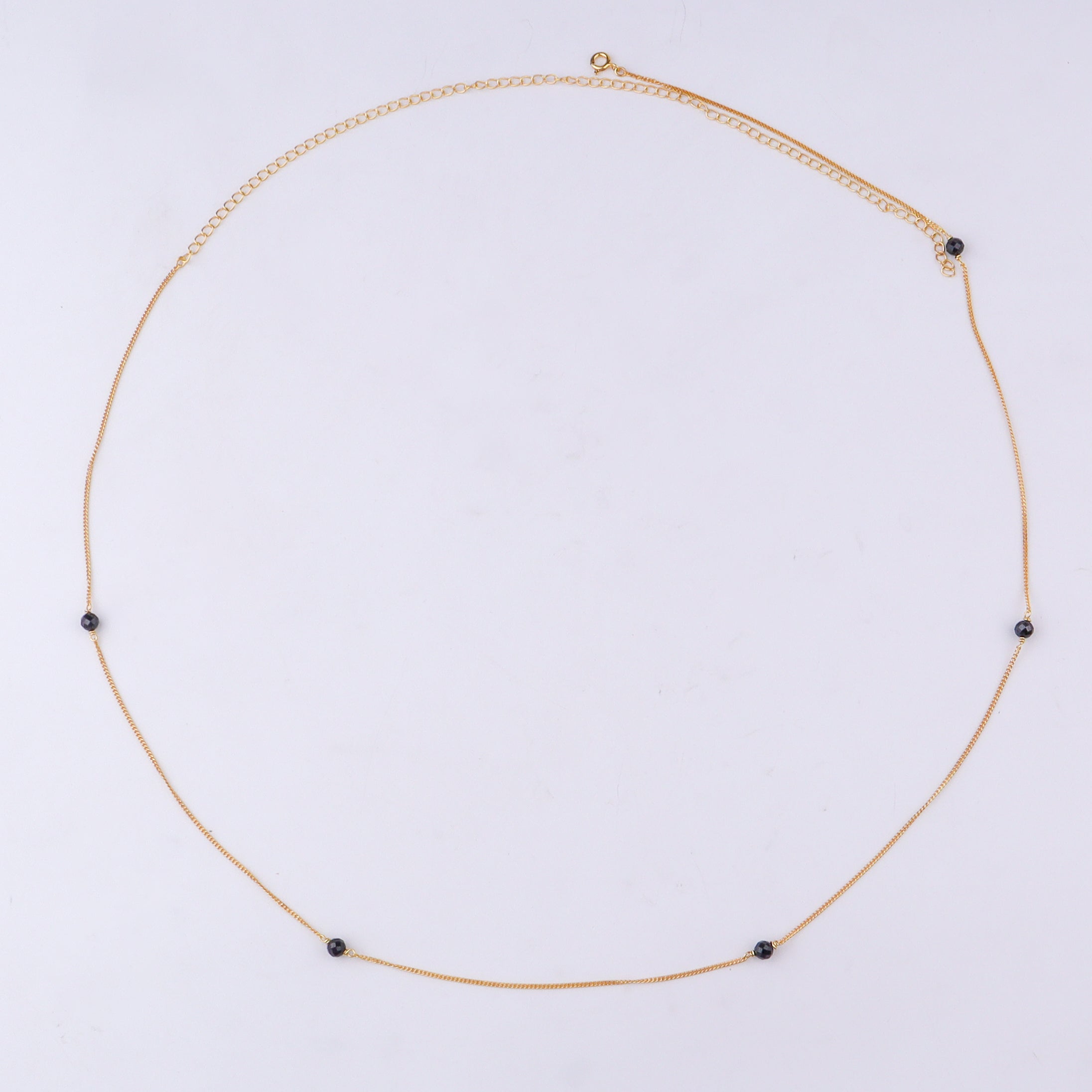 Close-up of gold chain with black beads