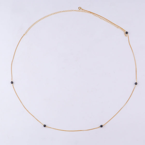 Close-up of gold chain with black beads
