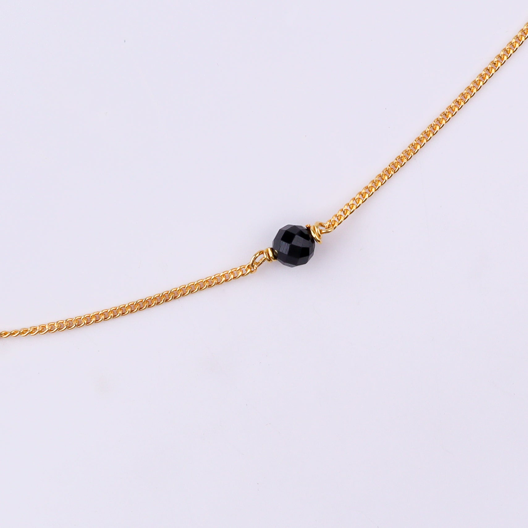 Gold chain with black beads on white background