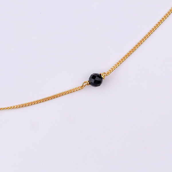 Gold chain with black beads on white background