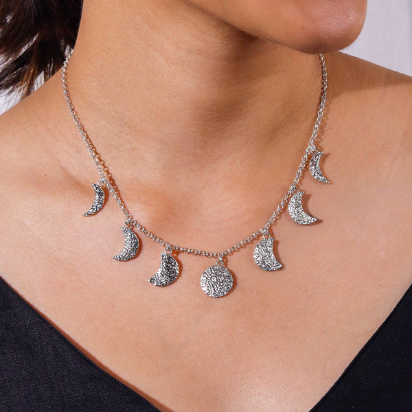 Close-up of silver moon phase necklace highlighting detailed moon motifs and polished sterling silver finish