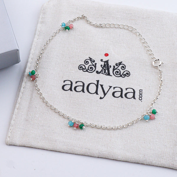 Silver anklet with beads on white fabric background