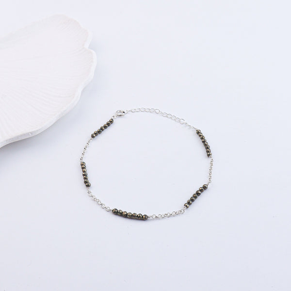 Silver chain anklet with black beads on white background