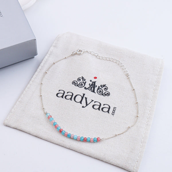Silver anklet with pastel beads on white background