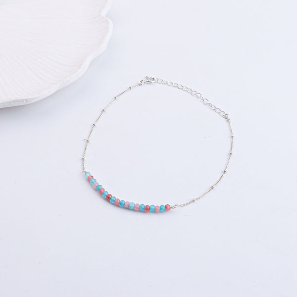 Close-up of silver anklet with pastel beads