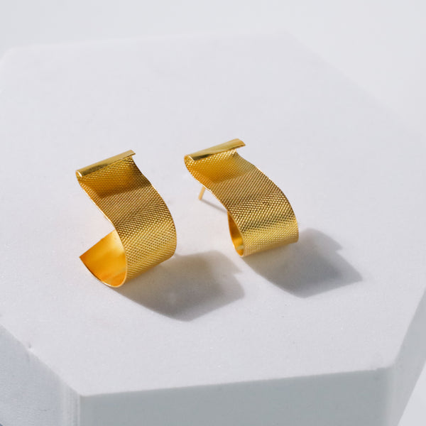 close-up of gold fold earrings on white background