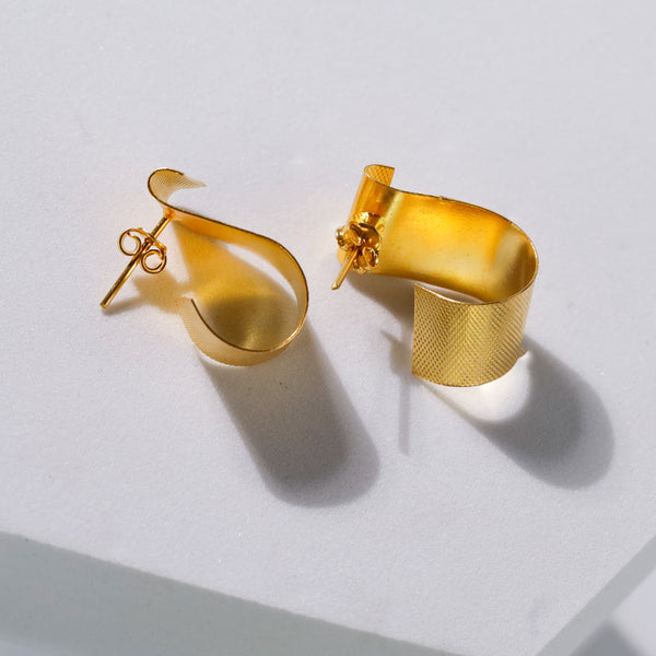 gold fold earrings on white surface