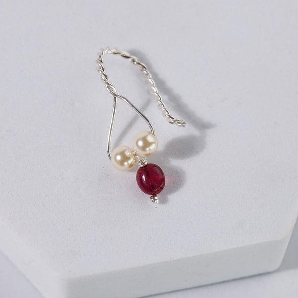 Close-up of silver twisted hoop earring with pearls and ruby