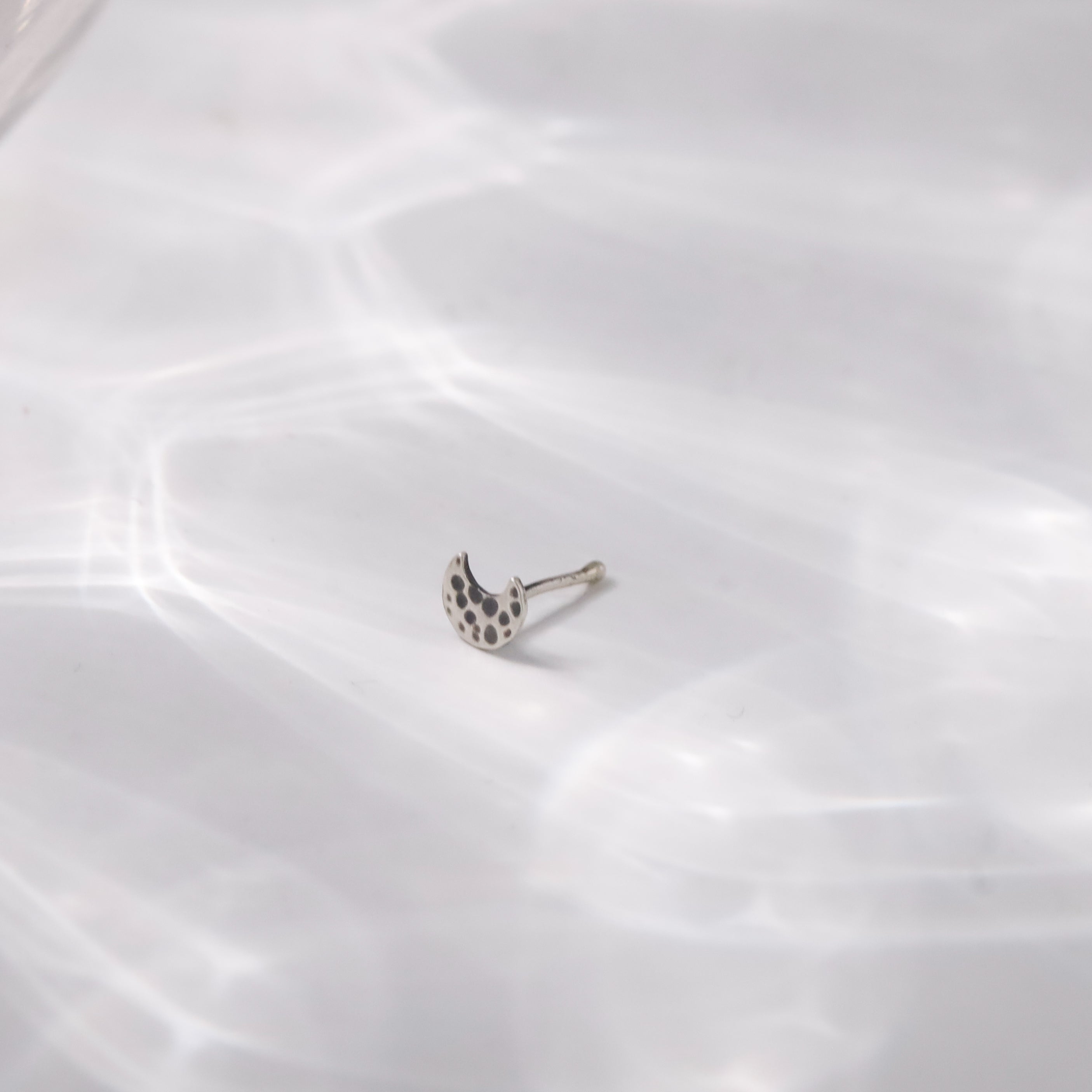 Flat lay of Silver Tiny Hammered Chandrakor Nose Pin